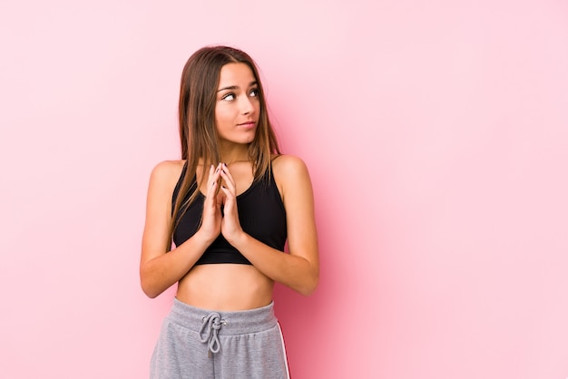 Young caucasian fitness woman posing in a pink wall making up plan in mind, setting up an idea.