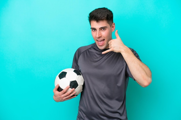 Young caucasian football player man isolated on blue background making phone gesture Call me back sign