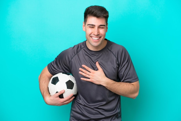 Young caucasian football player man isolated on blue background smiling a lot