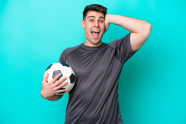 Young caucasian football player man isolated on blue background with surprise expression