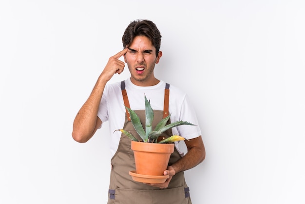 Young caucasian gardener man holding a plant isolated showing a disappointment gesture with forefinger.