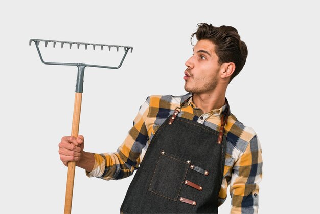 Young caucasian gardener man holding a plant isolated on white background