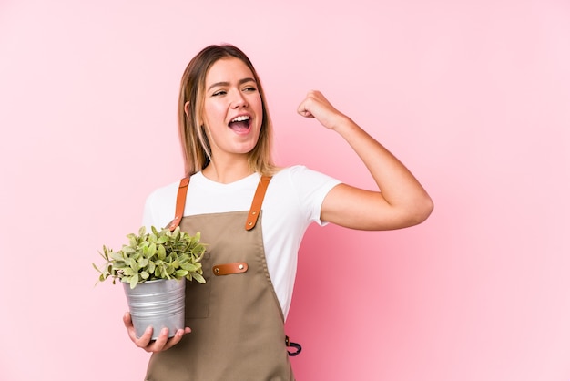 Giovane donna caucasica del giardiniere sul pugno alzante rosa dopo una vittoria, concetto del vincitore.