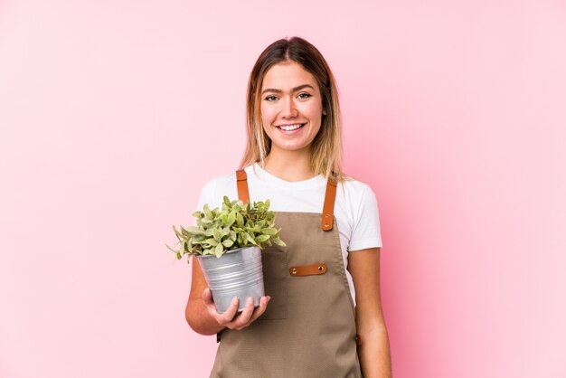 Giovane donna caucasica del giardiniere in una parete rosa felice, sorridente e allegra.