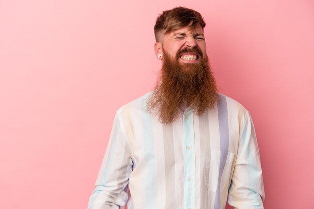 Young caucasian ginger man with long beard isolated on pink background dancing and having fun.