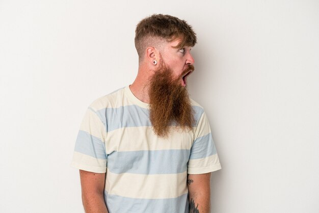 Young caucasian ginger man with long beard isolated on white background being shocked because of something she has seen.