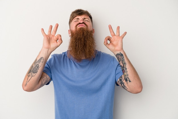 Young caucasian ginger man with long beard isolated on white background relaxes after hard working day, she is performing yoga.