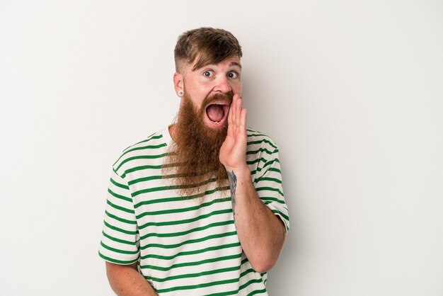 Young caucasian ginger man with long beard isolated on white background shouts loud, keeps eyes opened and hands tense.