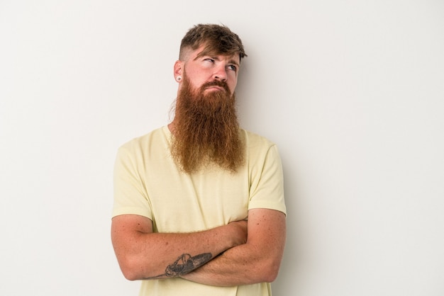Young caucasian ginger man with long beard isolated on white\
background tired of a repetitive task.