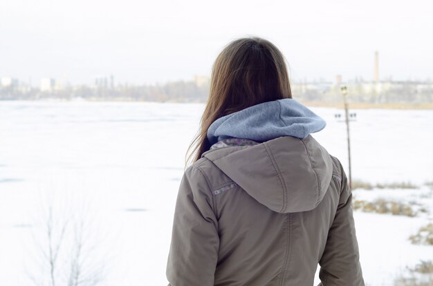 A young Caucasian girl in a brown coat