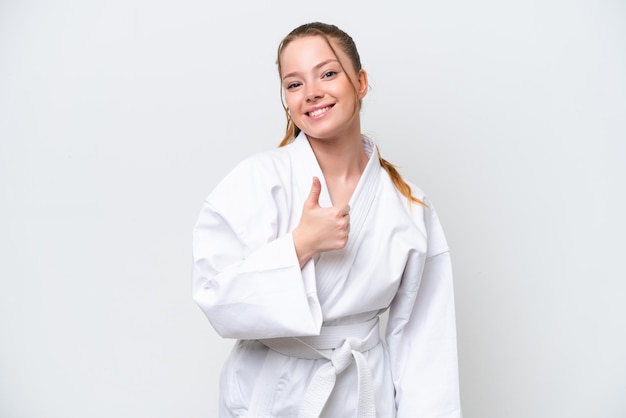 Young caucasian girl doing karate isolated on white background giving a thumbs up gesture