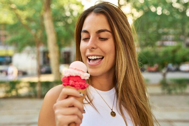 Foto giovane ragazza caucasica che gode del gelato nel parco