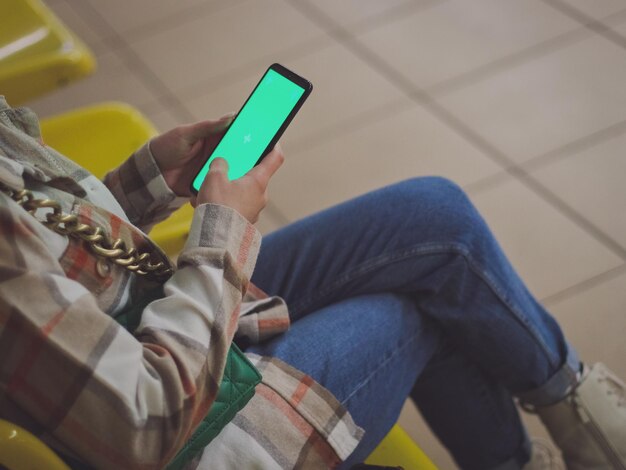 Young caucasian girl holds a smartphone with a green screen in her hands