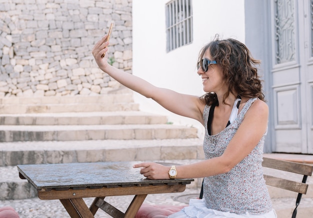 Young caucasian girl with sunglasses and brown hair taking a selfie smiling