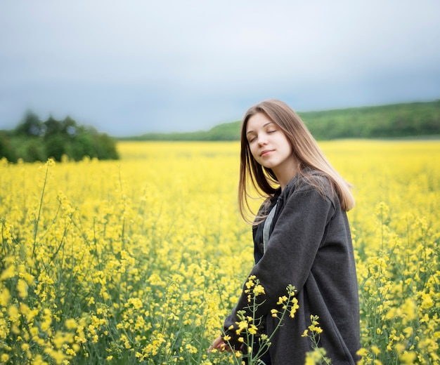 Молодая кавказская девушка на желтом поле рапса