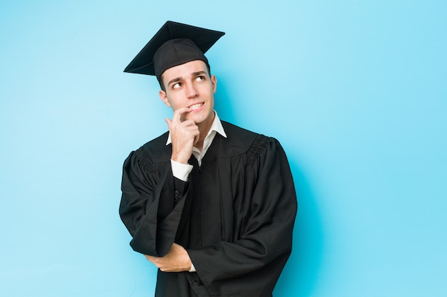 Young caucasian graduated man relaxed thinking about something looking at a copy space.