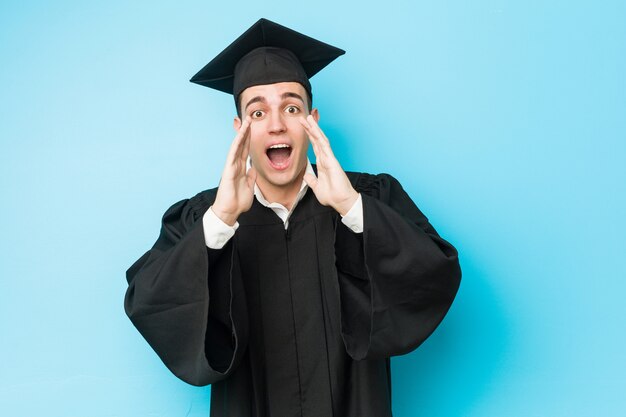 Young caucasian graduated man shouting excited to front.