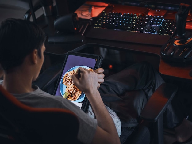 A young caucasian guy sits in a work chair and browses an online menu for ordering takeaway food