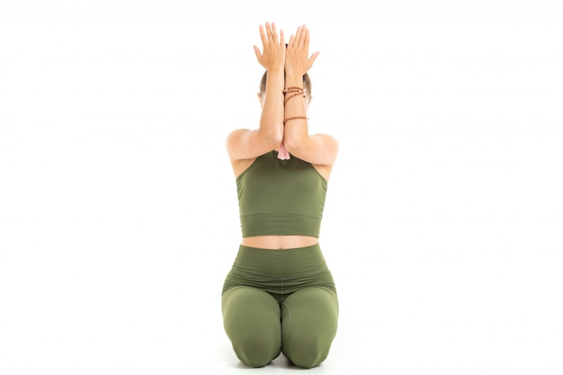 Young caucasian gymnast with athletic body sits on a floor with closed eyes, doing yoga and meditating isolated on white background