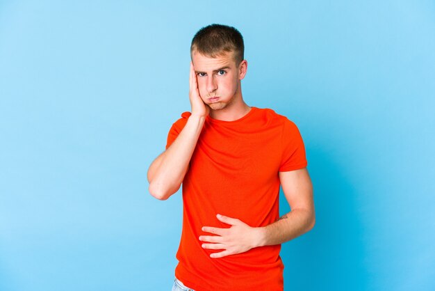 Young caucasian handsome man blows cheeks, has tired expression. Facial expression concept.