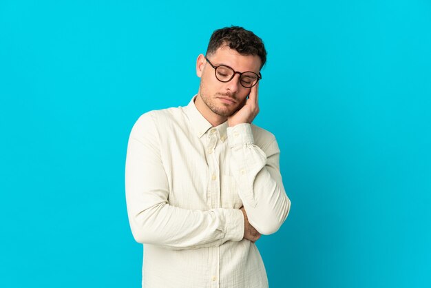 Young caucasian handsome man on blue with headache