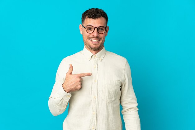 Young caucasian handsome man on blue with surprise facial expression