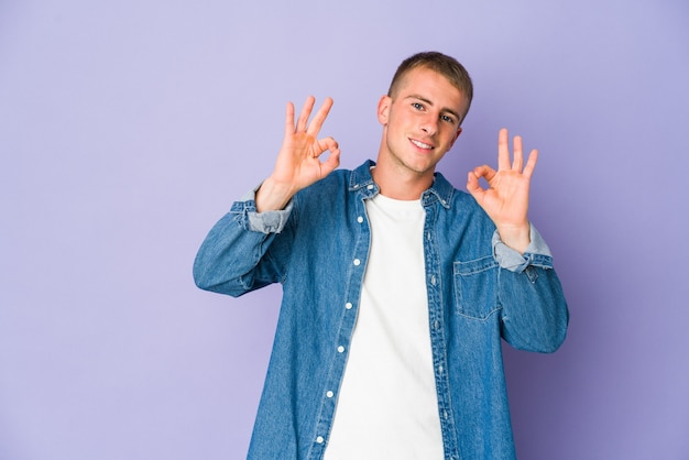 Young caucasian handsome man cheerful and confident showing ok gesture.