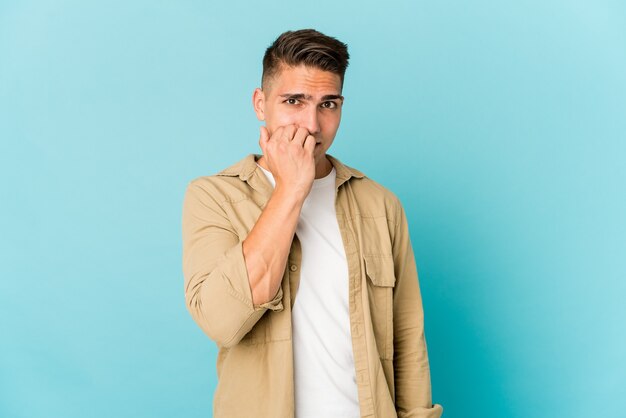 Young caucasian handsome man isolated biting fingernails, nervous and very anxious.