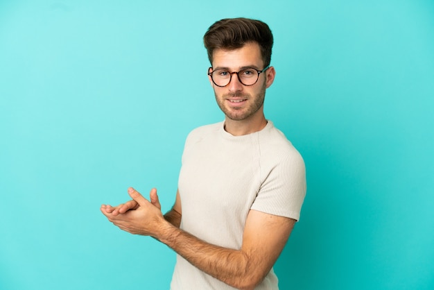 Young caucasian handsome man isolated on blue background applauding