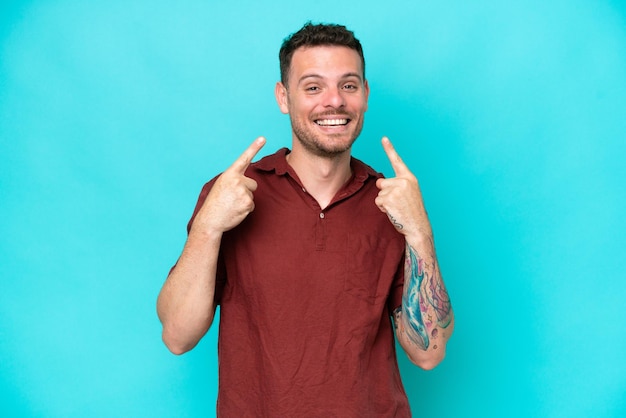 Young caucasian handsome man isolated on blue background giving a thumbs up gesture