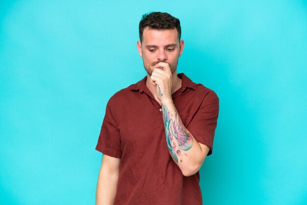 Young caucasian handsome man isolated on blue background having doubts