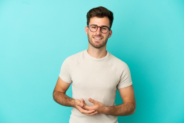 Young caucasian handsome man isolated on blue background laughing