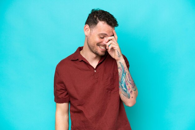 Young caucasian handsome man isolated on blue background laughing