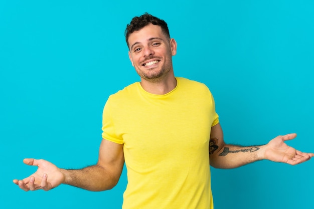 Young caucasian handsome man isolated on blue wall happy and smiling