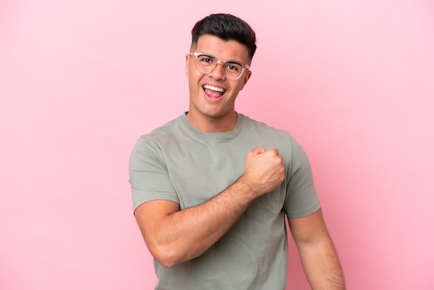 Young caucasian handsome man isolated on pink background celebrating a victory