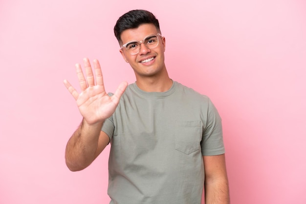 Young caucasian handsome man isolated on pink background counting five with fingers