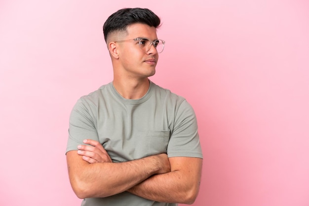 Young caucasian handsome man isolated on pink background looking to the side