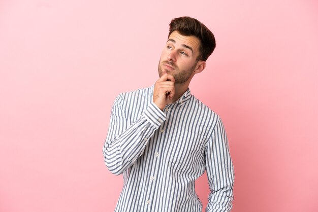 Young caucasian handsome man isolated on pink background and looking up