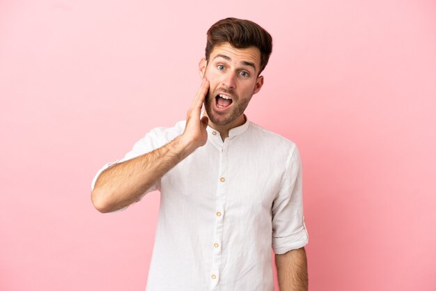 Young caucasian handsome man isolated on pink background with surprise and shocked facial expression