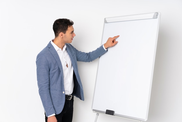Young caucasian handsome man isolated on purple wall giving a presentation on white board