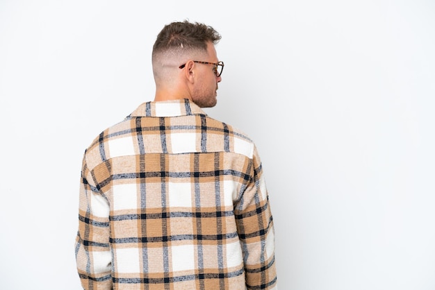 Young caucasian handsome man isolated on white background in back position and looking side