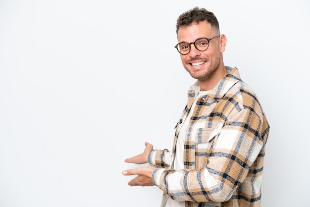 Young caucasian handsome man isolated on white background extending hands to the side for inviting to come