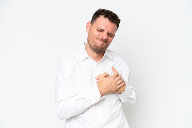 Young caucasian handsome man isolated on white background having a pain in the heart