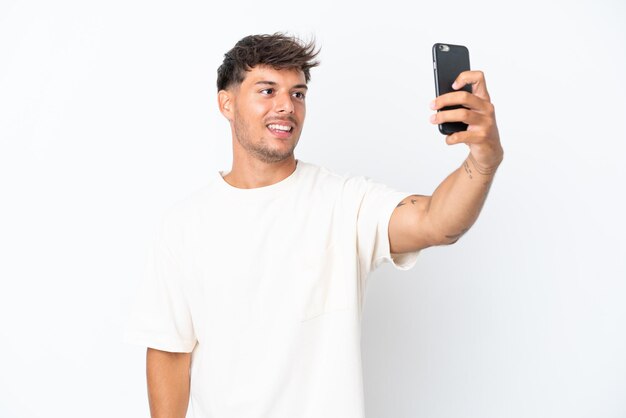 Young caucasian handsome man isolated on white background making a selfie