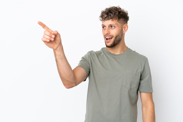 Young caucasian handsome man isolated on white background pointing away