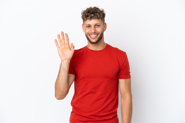 Young caucasian handsome man isolated on white background saluting with hand with happy expression