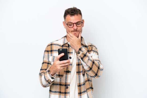 Young caucasian handsome man isolated on white background thinking and sending a message