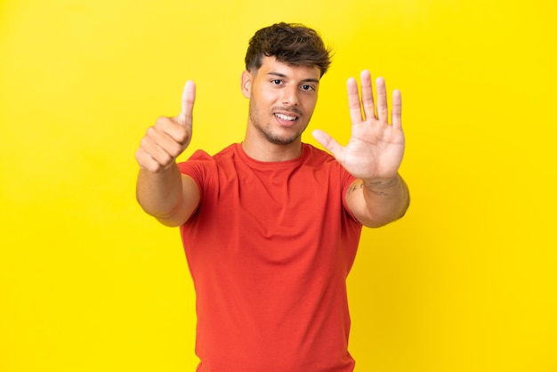 Young caucasian handsome man isolated on yellow background counting six with fingers