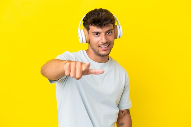 Young caucasian handsome man isolated on yellow background listening music