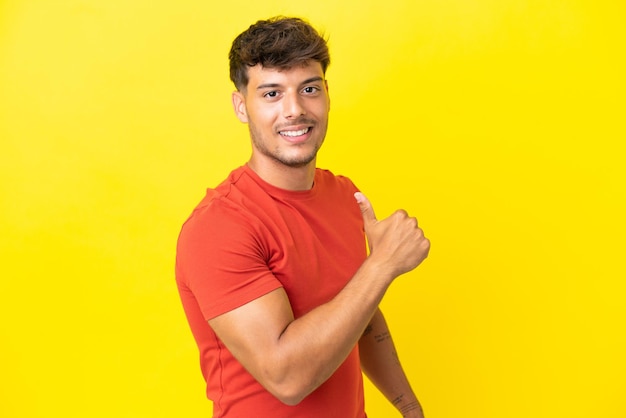 Young caucasian handsome man isolated on yellow background proud and self-satisfied